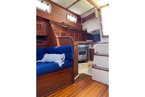 Slide: The Image of Interior of a 1988 Tartan 31 sailboat with wooden finishes and blue seating. - 8