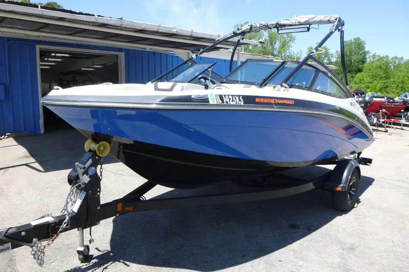 The Image of 2014 Yamaha AR192 boat on trailer, blue and white, parked outside a blue building. - 2