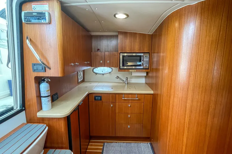 Slide: The Image of 2004 Tiara Yachts 3800 Open interior kitchen with wood cabinetry and modern appliances. - 23