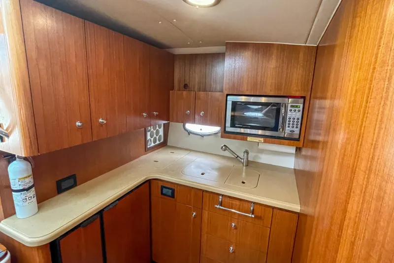 Slide: The Image of 2004 Tiara Yachts 3800 Open galley with wood cabinetry, microwave, and sink. - 24