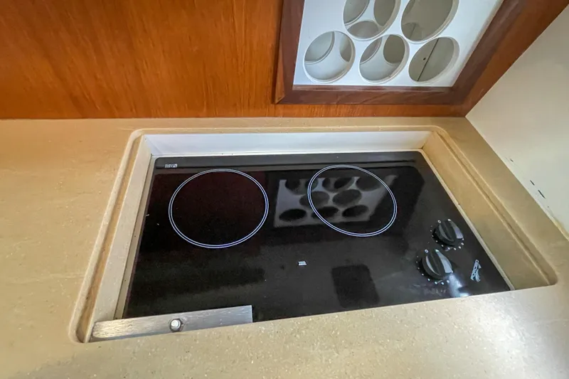 Slide: The Image of 2004 Tiara Yachts 3800 Open kitchen with electric stovetop and wooden cabinetry. - 26