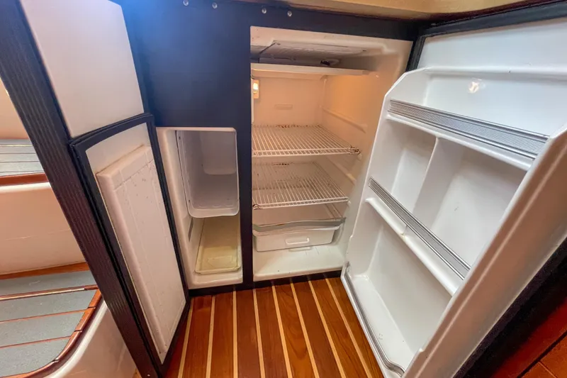 Slide: The Image of Open refrigerator inside 2004 Tiara Yachts 3800 Open, featuring wooden flooring and spacious shelving. - 27