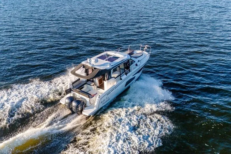 Slide: The Image of 2021 Jeanneau NC 1095 cruising on open water, rear view. - 2