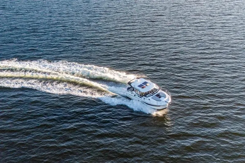 Slide: The Image of 2021 Jeanneau NC 1095 cruising on open water, leaving a wake behind. - 5