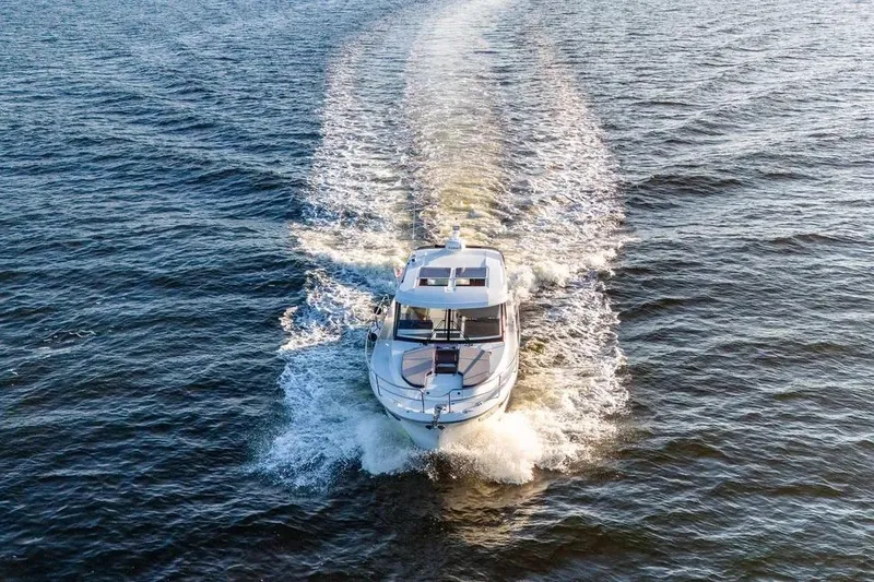 Slide: The Image of 2021 Jeanneau NC 1095 cruising on open water, creating a dynamic wake. - 9