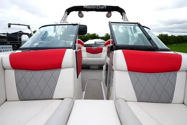 Slide: The Image of 2015 MasterCraft X20 boat interior with red and gray seating, open deck view. - 11
