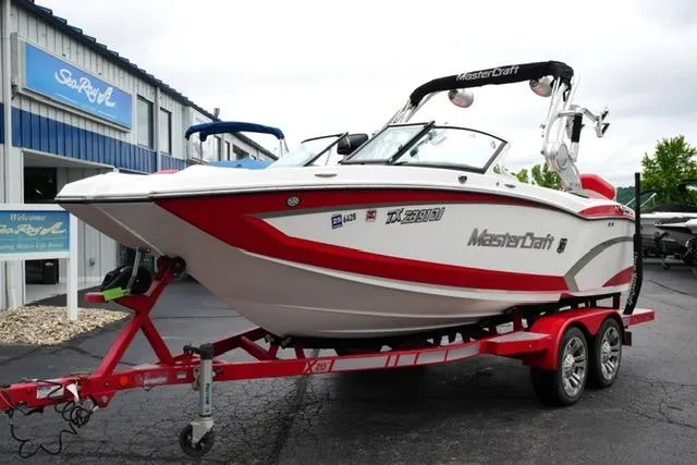 Slide: The Image of 2015 MasterCraft X20 boat on red trailer outside dealership. - 2