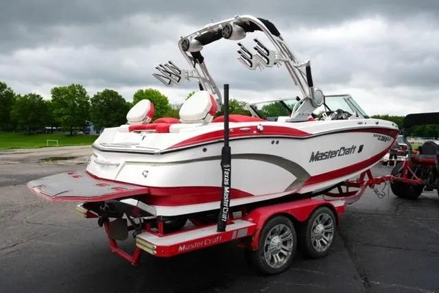 Slide: The Image of 2015 MasterCraft X20 boat on trailer, white and red design, parked outdoors. - 5