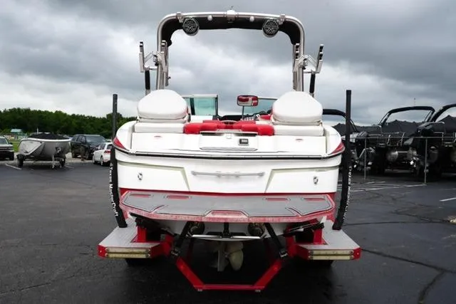 Slide: The Image of 2015 MasterCraft X20 boat, rear view, parked on asphalt under cloudy sky. - 6