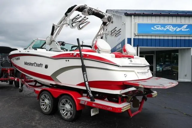 Slide: The Image of 2015 MasterCraft X20 boat on trailer, red and white design, parked outside dealership. - 7
