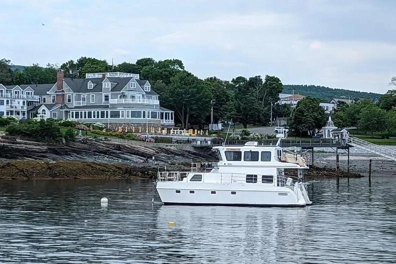 The Image of 2009 Endeavour 40 Skylounge yacht anchored near a scenic coastal town with historic buildings. - 1