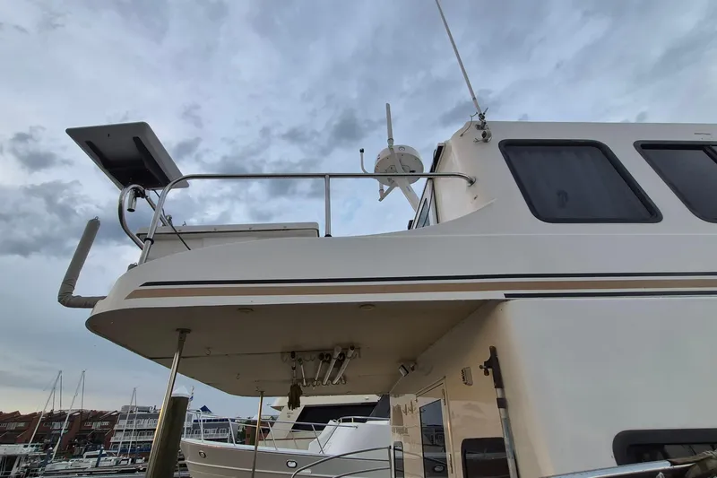 Slide: The Image of 2009 Endeavour 40 Skylounge yacht docked, showcasing upper deck and windows under cloudy sky. - 43