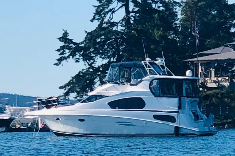 The Image of 2005 Silverton 39 Motor Yacht docked near trees and a house. - 0