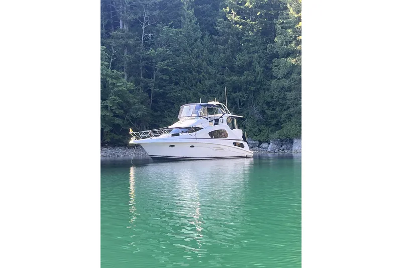 Slide: The Image of 2005 Silverton 39 Motor Yacht anchored on serene green water, surrounded by lush forest. - 46