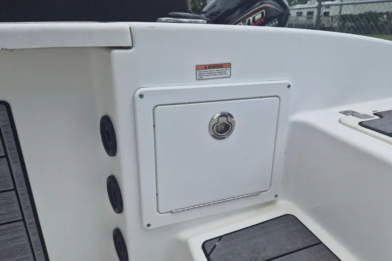 Slide: The Image of 2024 NauticStar 251 Hybrid boat storage compartment with secure latch and warning label. - 10