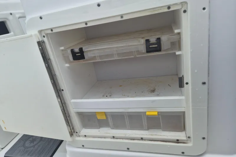 Slide: The Image of Storage compartment on a 2024 NauticStar 251 Hybrid boat, featuring tackle boxes. - 16