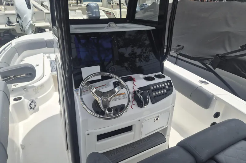Slide: The Image of 2024 NauticStar 251 Hybrid boat cockpit with steering wheel and control panel. - 18