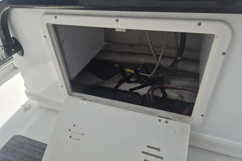 Slide: The Image of Open storage compartment on a 2024 NauticStar 251 Hybrid boat, showing wiring and interior space. - 20
