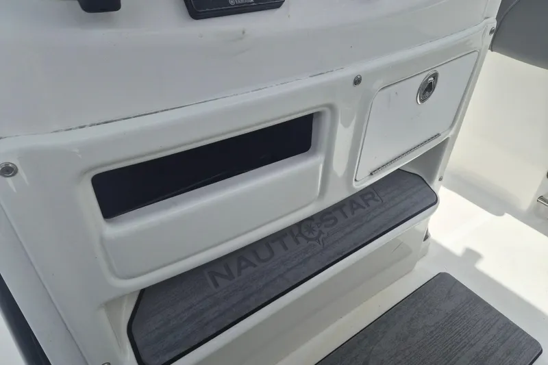 Slide: The Image of 2024 NauticStar 251 Hybrid boat interior with storage compartment and branded step. - 21