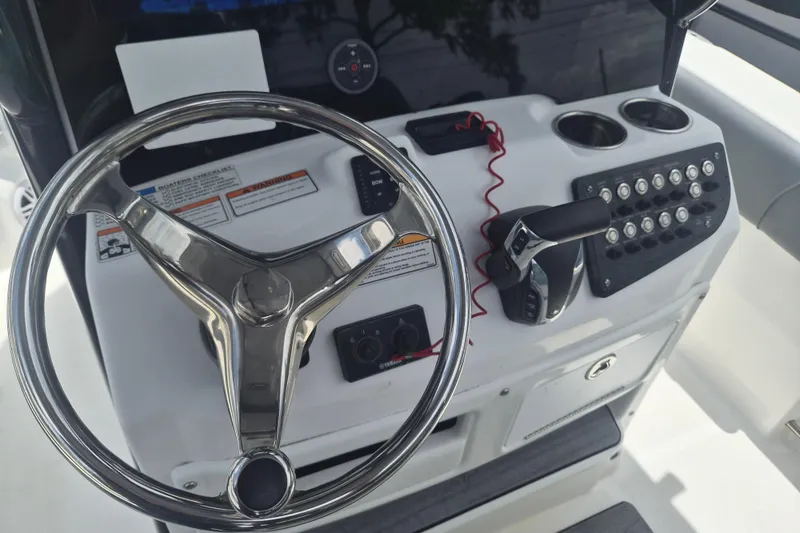 Slide: The Image of 2024 NauticStar 251 Hybrid boat dashboard with steering wheel and control panel. - 22