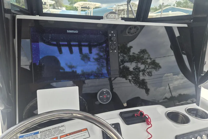 Slide: The Image of 2024 NauticStar 251 Hybrid boat dashboard with Simrad display and steering wheel. - 23