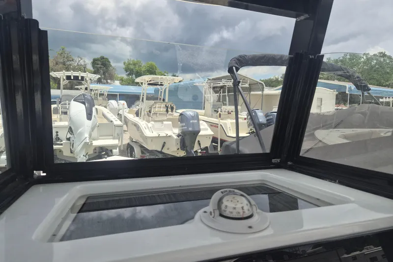 Slide: The Image of 2024 NauticStar 251 Hybrid boats viewed through a window, under cloudy skies. - 24