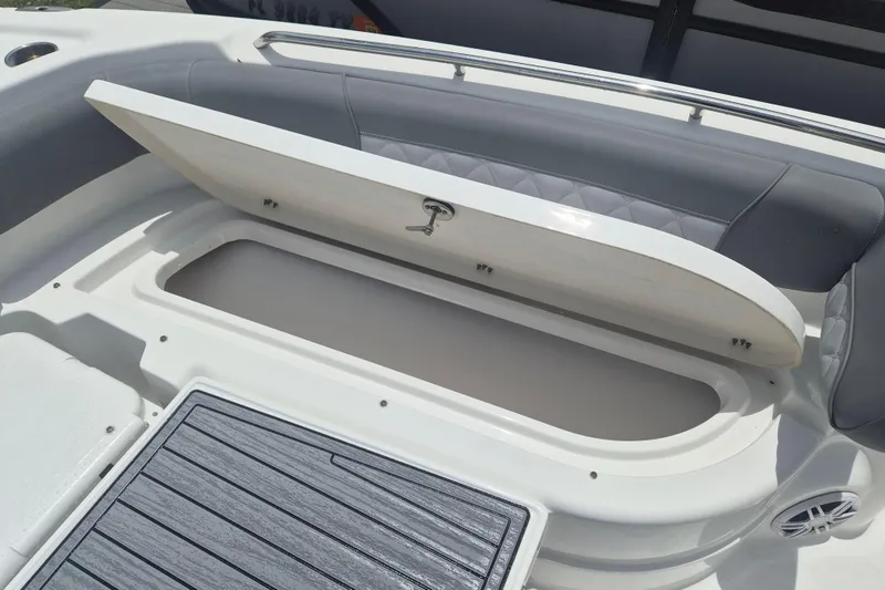 Slide: The Image of 2024 NauticStar 251 Hybrid boat storage compartment with open lid and cushioned seating. - 30