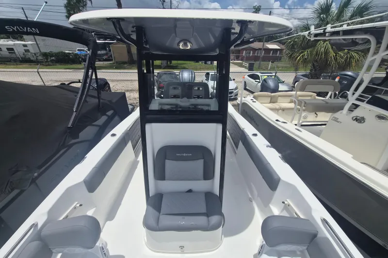 Slide: The Image of 2024 NauticStar 251 Hybrid boat interior with seating and console, docked outdoors. - 34