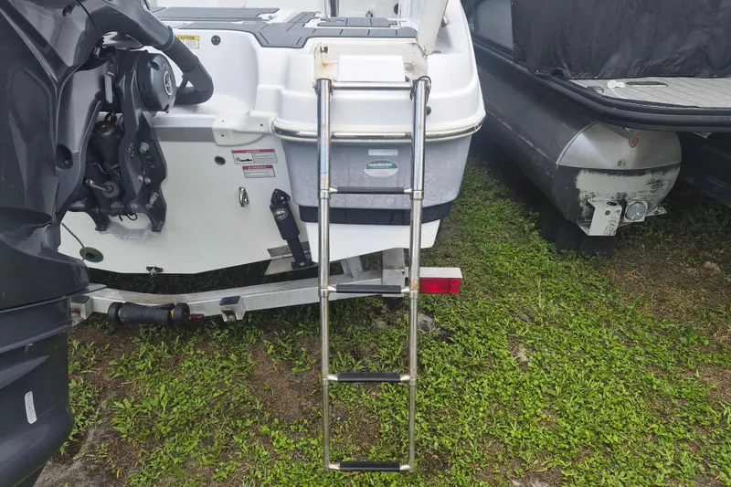 Slide: The Image of 2024 NauticStar 251 Hybrid boat with ladder on grassy surface. - 6