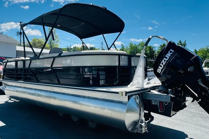 Slide: The Image of 2026 Berkshire 24 RFX CTS pontoon boat with Suzuki outboard motor under clear blue sky. - 2