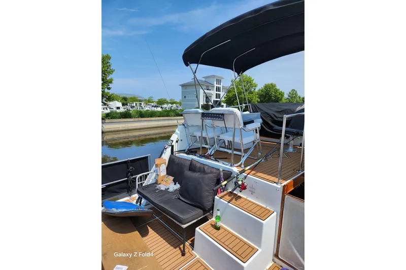 Slide: The Image of 1990 Prowler Aft Cabin boat with seating, fishing rods, and scenic waterfront view. - 3