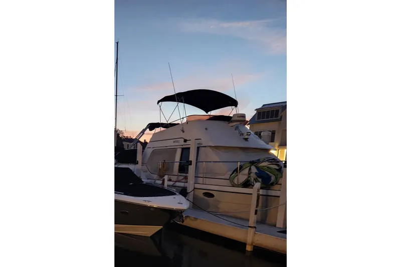 Slide: The Image of 1990 Prowler Aft Cabin yacht docked at sunset with a covered upper deck. - 4