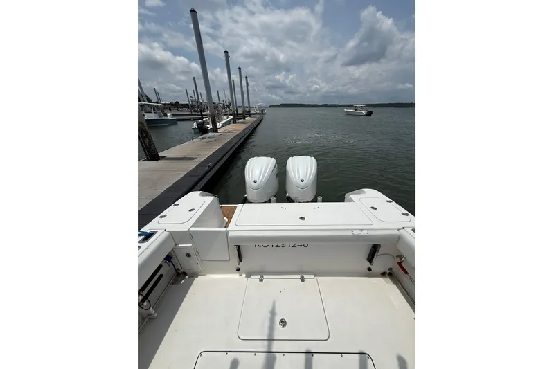 Slide: The Image of 2018 Edgewater 320CC boat docked, featuring dual outboard motors under a cloudy sky. - 14