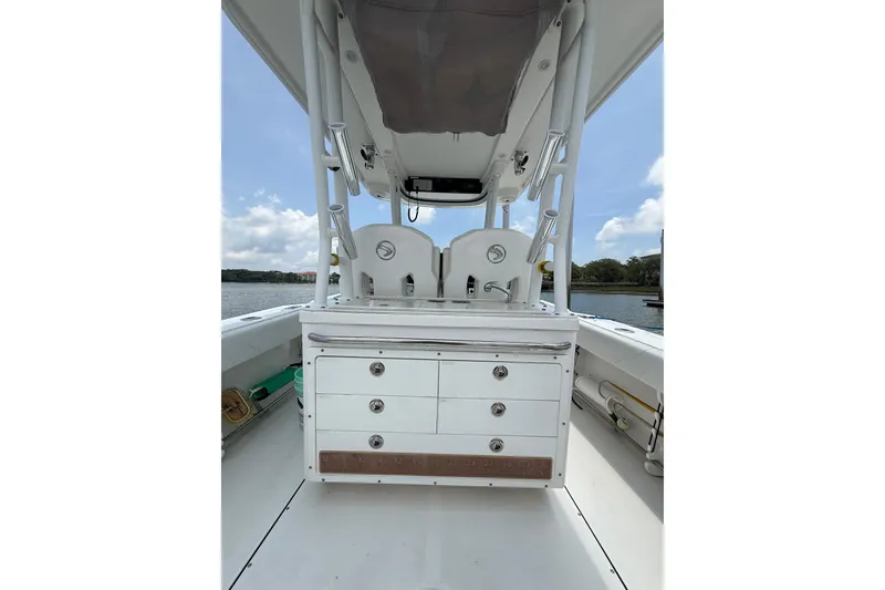 Slide: The Image of 2018 Edgewater 320CC boat interior with storage drawers and seating, under a clear sky. - 19