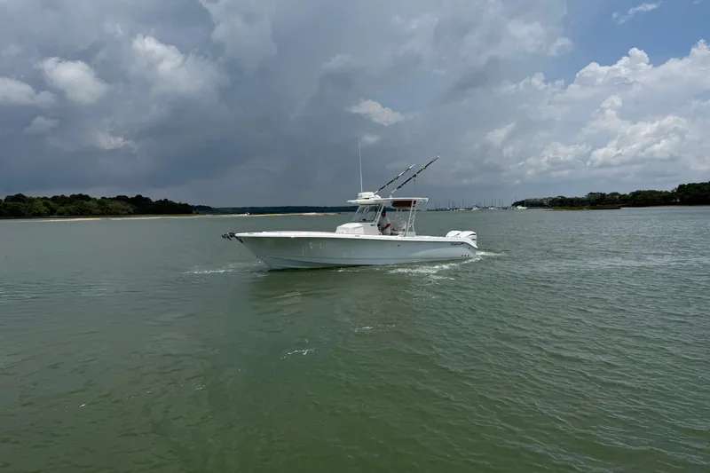 Slide: The Image of 2018 Edgewater 320CC boat cruising on a calm lake under cloudy skies. - 2