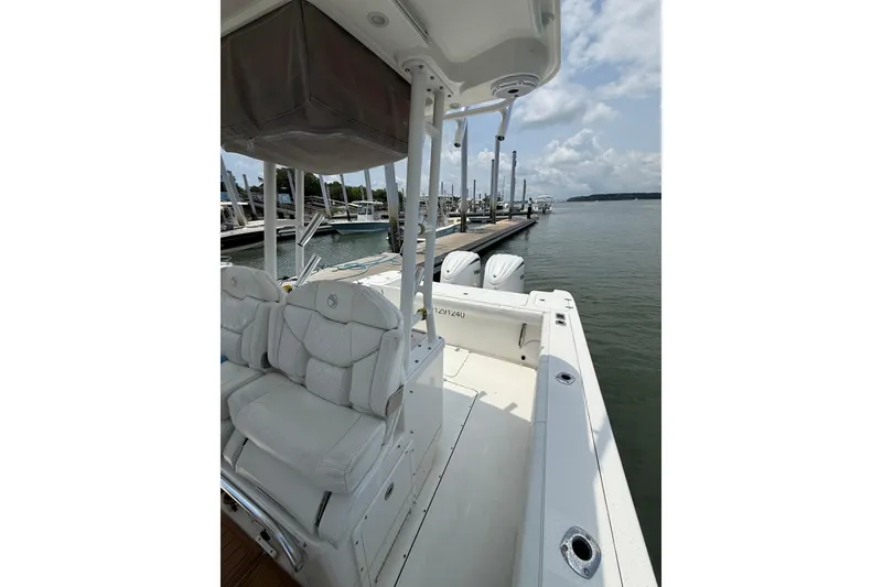 Slide: The Image of 2018 Edgewater 320CC boat docked, featuring white seating and dual engines. - 22