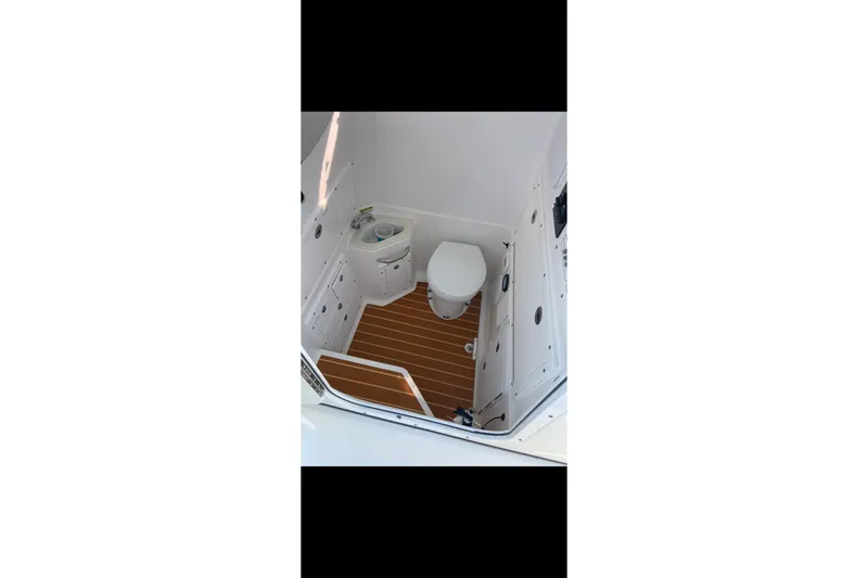 Slide: The Image of Interior of 2018 Edgewater 320CC boat featuring a compact marine toilet and sink. - 23