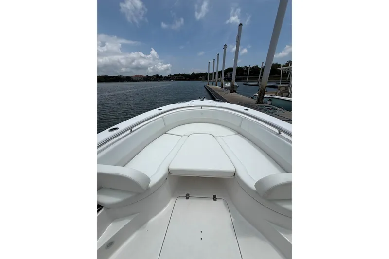 Slide: The Image of 2018 Edgewater 320CC boat interior with white seating, docked by a calm waterfront. - 5