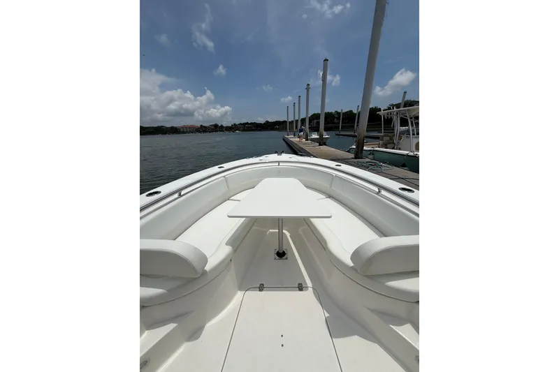Slide: The Image of 2018 Edgewater 320CC boat docked, featuring spacious seating and table under a clear sky. - 6
