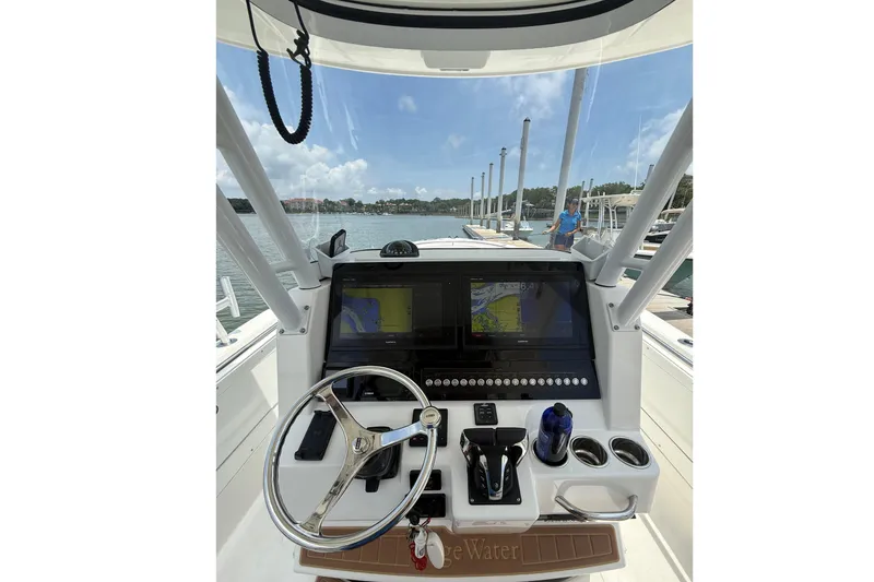 Slide: The Image of Edgewater 320CC 2018 boat helm with navigation screens and steering wheel at marina. - 9