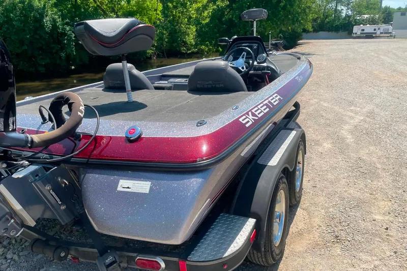 Slide: The Image of 2014 Skeeter ZX20 bass boat with dual axle trailer, parked on gravel near trees. - 3