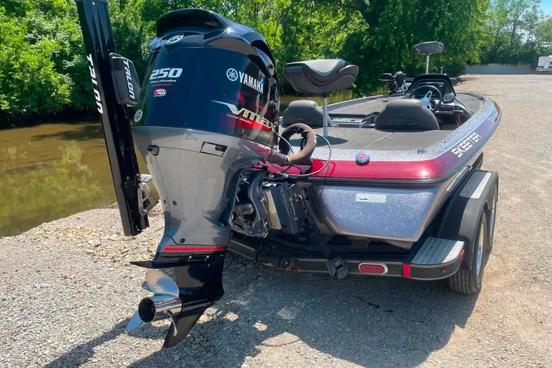 Slide: The Image of 2014 Skeeter ZX20 boat with Yamaha 250 engine, parked near a riverbank. - 4