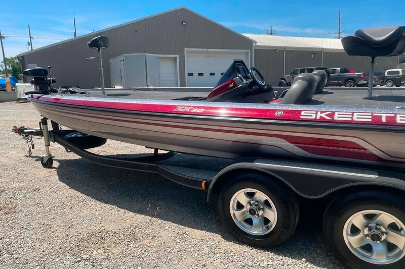 Slide: The Image of 2014 Skeeter ZX20 bass boat on trailer, parked outdoors near a warehouse. - 6