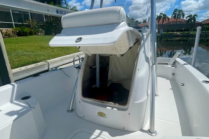 Slide: The Image of 2015 Glasstream 228 TE boat with open storage compartment, docked near lush greenery. - 11