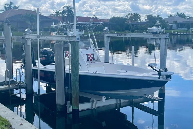 Slide: The Image of 2015 Glasstream 228 TE boat docked on a lift in a serene waterfront setting. - 2
