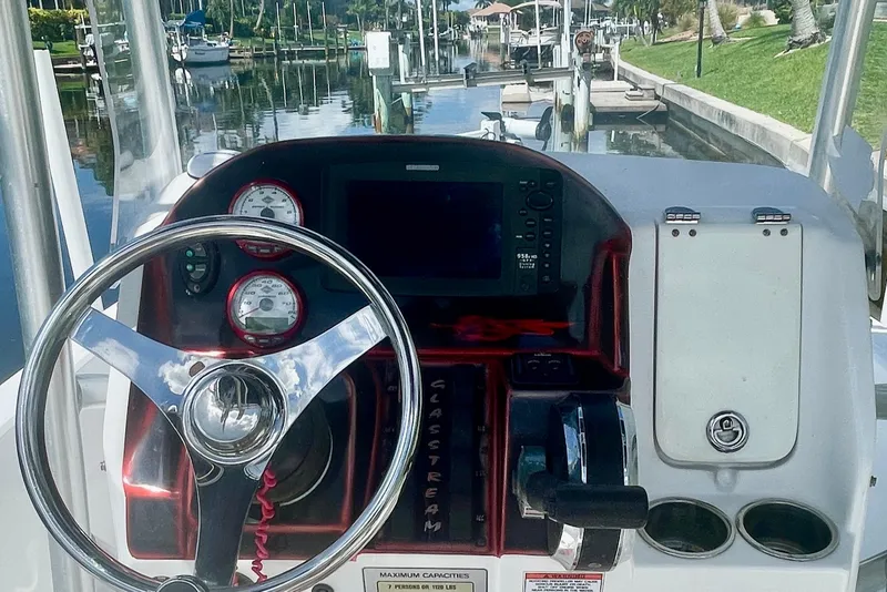 Slide: The Image of 2015 Glasstream 228 TE boat dashboard with steering wheel and gauges, docked by a canal. - 7