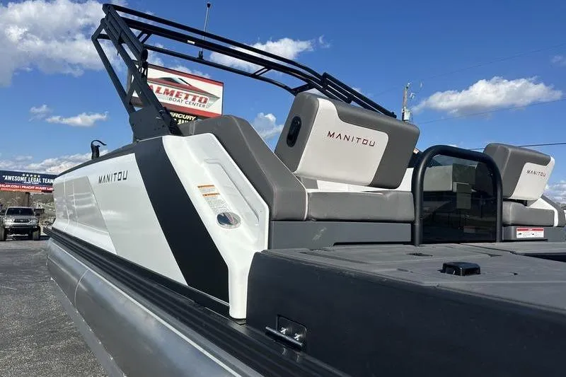 Slide: The Image of 2024 Manitou Cruise 22 Max Bench V-Toon pontoon boat under a clear blue sky. - 5