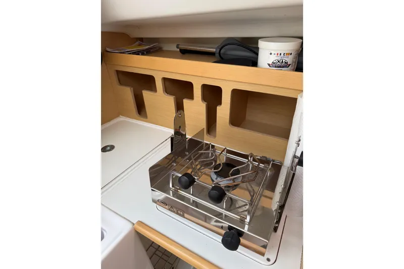 Slide: The Image of Compact kitchen area in a 2014 Beneteau FIRST 25 S sailboat with stove and storage. - 18