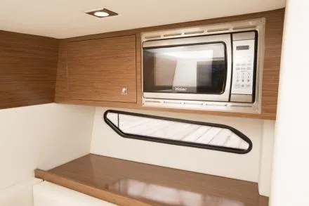 Slide: The Image of Manufacturer Provided Image: 2015 Cruisers Sport Series 328 Bow Rider interior with microwave and wooden cabinetry. - 24