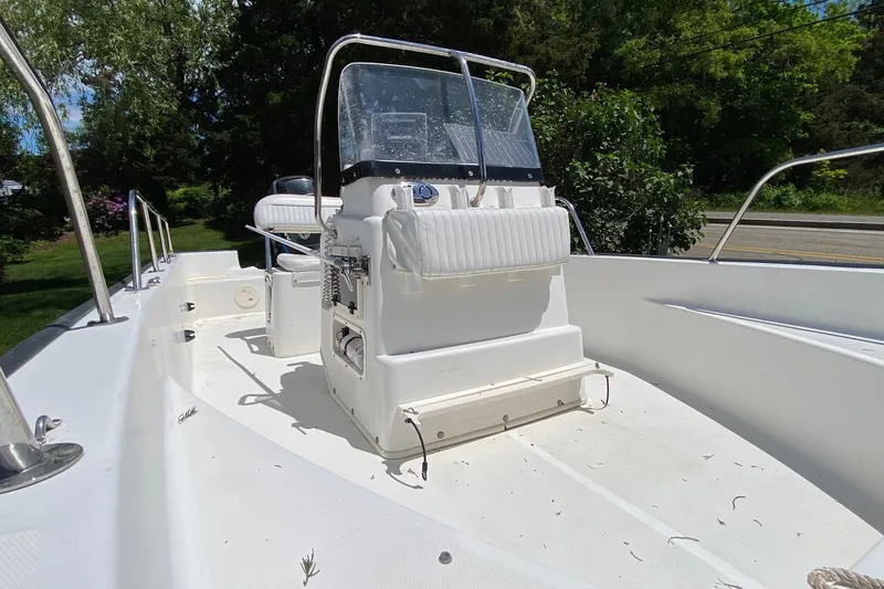 Slide: The Image of 2004 Boston Whaler 170 Montauk boat interior with console and seating, surrounded by greenery. - 9
